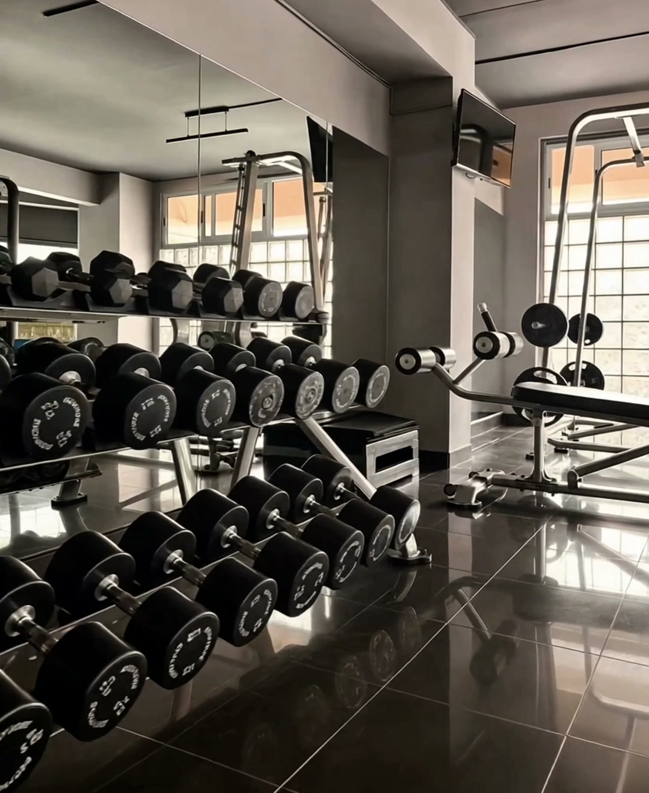 Sala de peso libre de Fitness Center Santander: rack de mancuernas negras sobre suelo pulido
